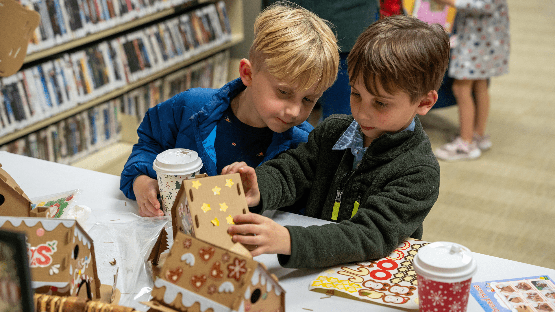 Image description: Two children are building a gingerbread house together.