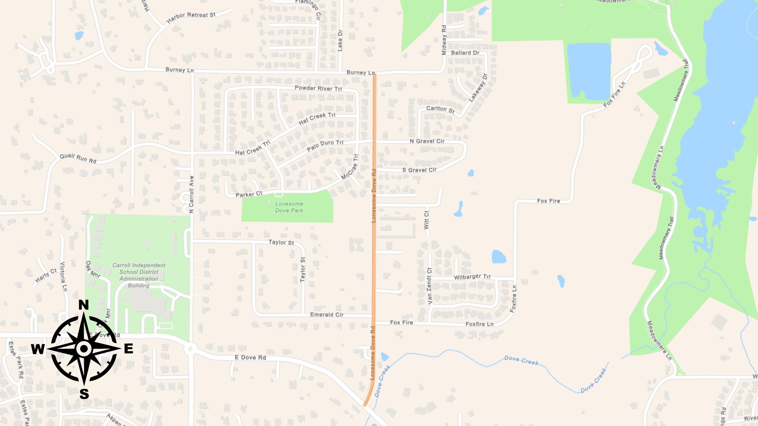 A map showing a suburban area with streets, houses, parks, and lakes. A north-south road is highlighted in orange. A compass rose is at the bottom left, and green areas mark parks and natural spaces on the right side.