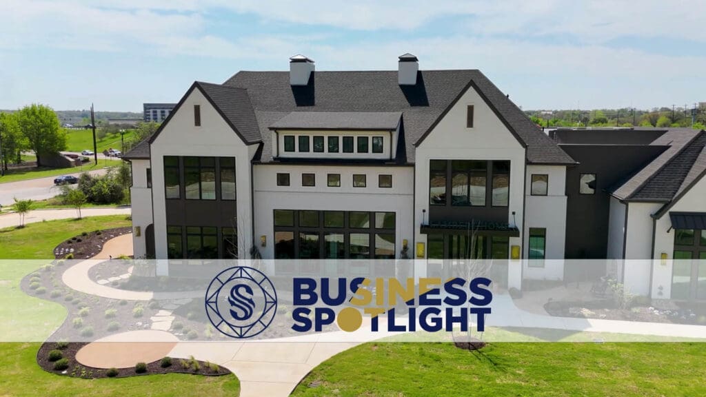 A modern, two-story building with large windows and landscaped grounds is shown under a sunny sky. The words "Business Spotlight" with a circular logo are overlaid at the bottom of the image.